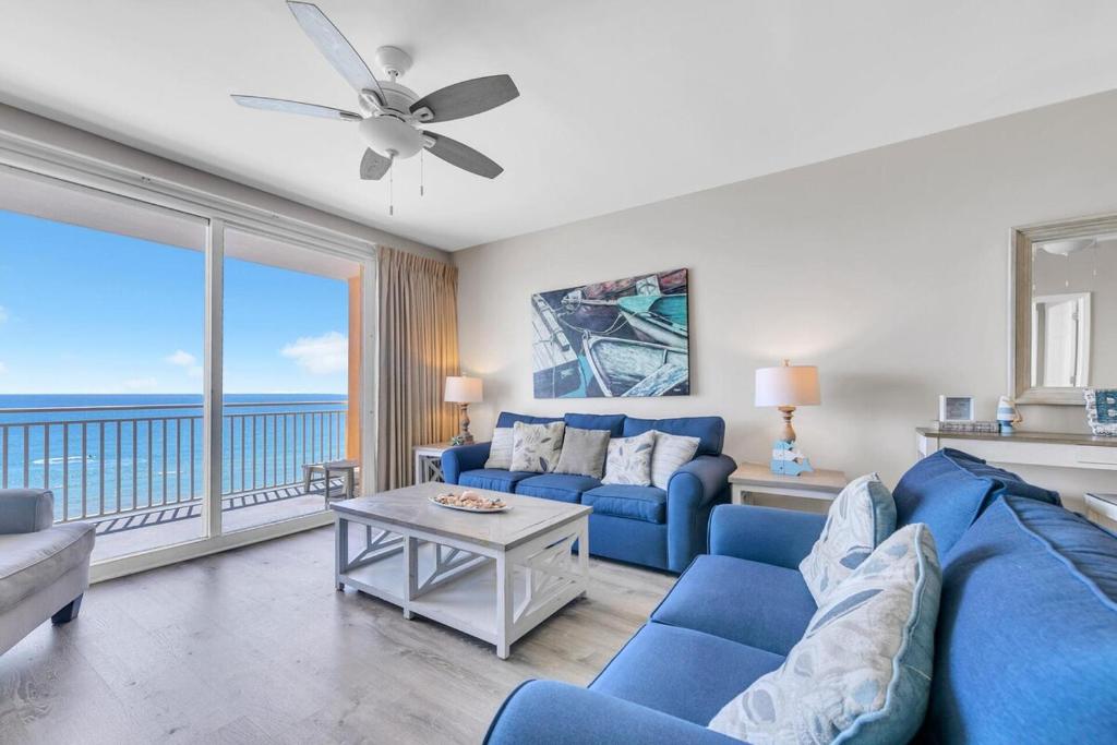 een woonkamer met een blauwe bank en een groot raam bij Beachfront Condo in Panama City Beach! in Panama City Beach