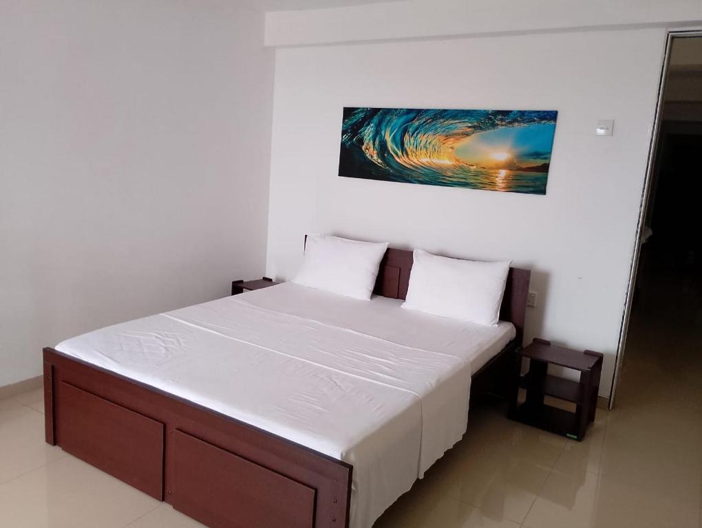 a bedroom with a bed with a painting on the wall at Travelhubs Rooms in Kandy