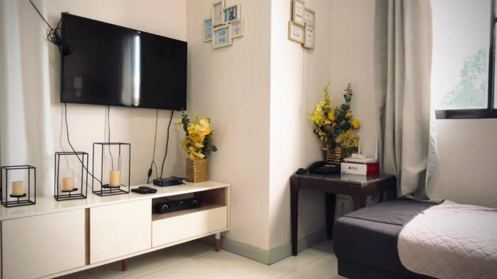 een slaapkamer met een bed en een tv aan de muur bij Spacious Central Davao City Getaway - Spacious Apartment with Shared Pool in Cabaguio