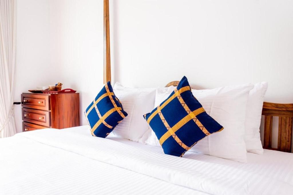 a white bed with blue and yellow pillows on it at Villa TIS in Galle