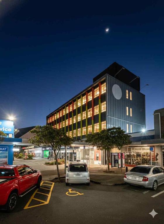 a large building with cars parked in a parking lot at The Post Hotel in Porirua
