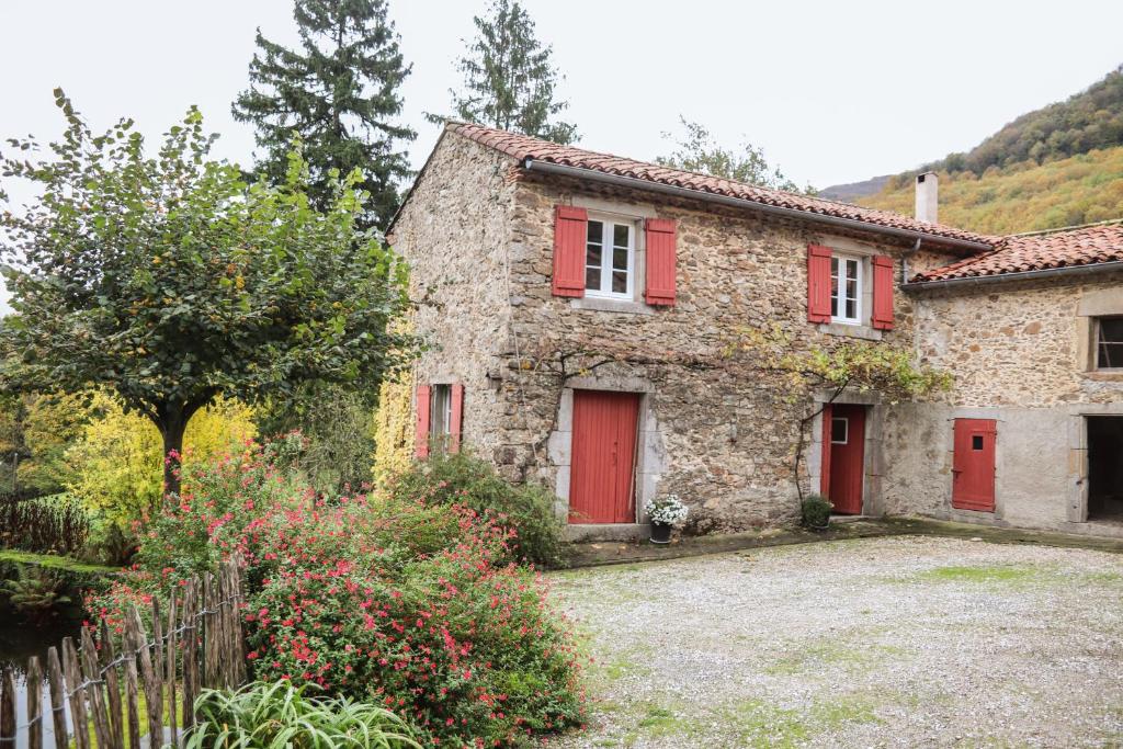 a stone house with red doors and a fence at Le Refuge de Bruno in Saint-Amans-Soult