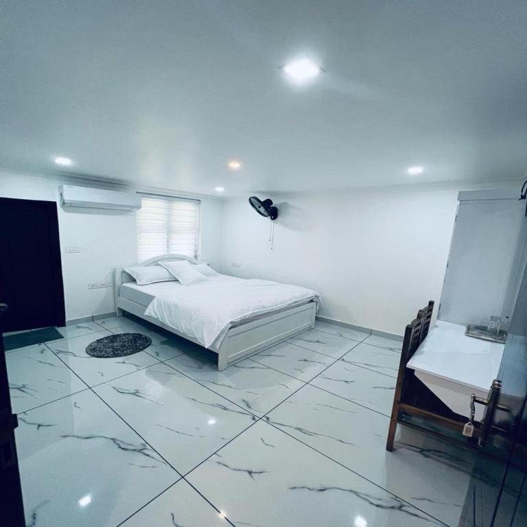 a white bedroom with a bed and a tiled floor at Riftha La Banquet in Kannur