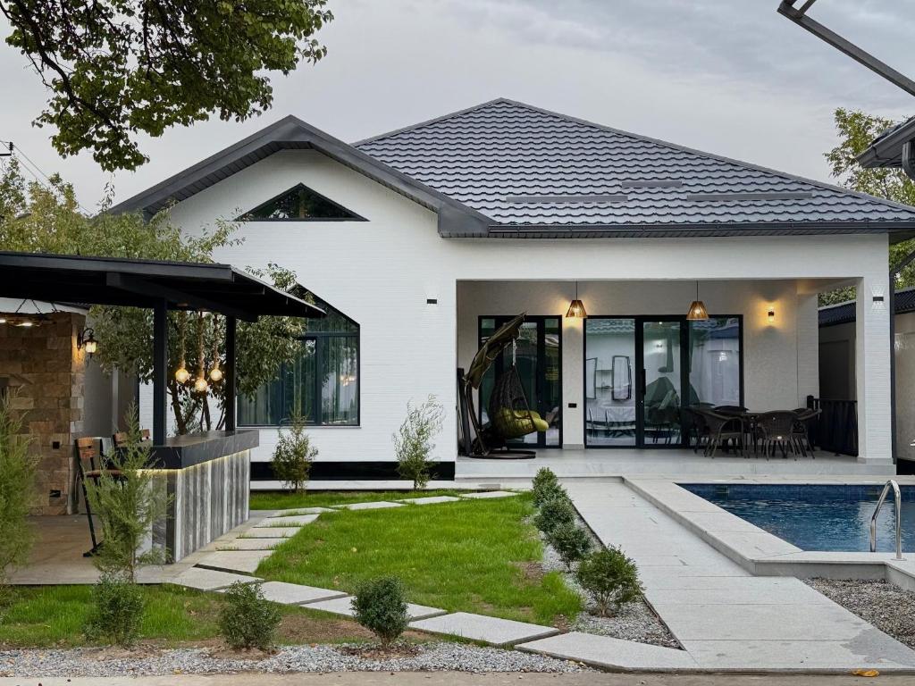 ein weißes Haus mit einem Pool in der Unterkunft Дачный Дом in Schymkent