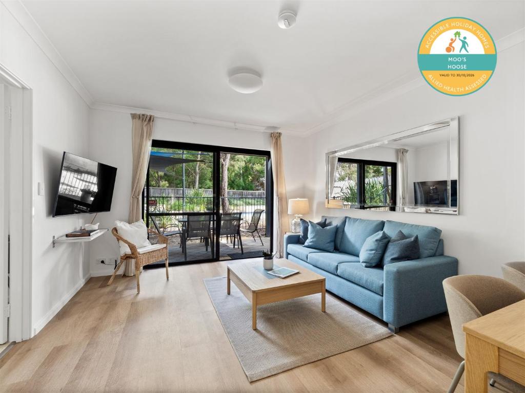 Una sala de estar con un sofá azul y una mesa. en Moo's Hoose, en Margaret River Town