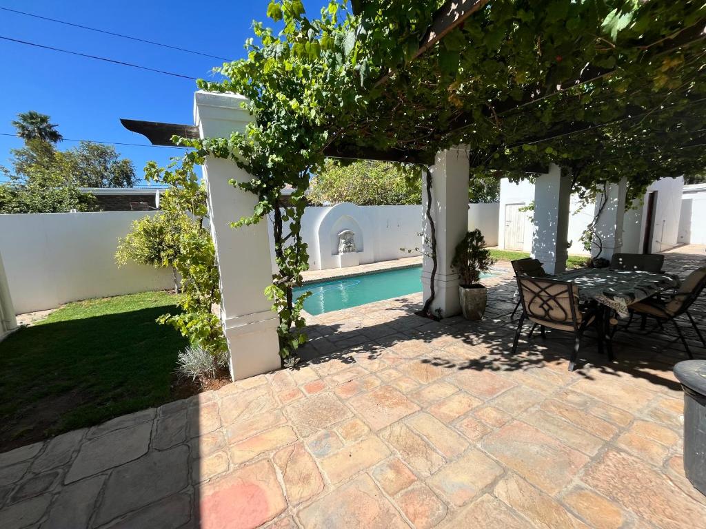 a patio with a table and chairs under a pergola at Toni's Cottage in Graaff-Reinet