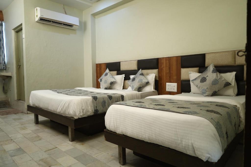 a hotel room with two beds and a heater at Hotel Aasopalav in Ahmedabad