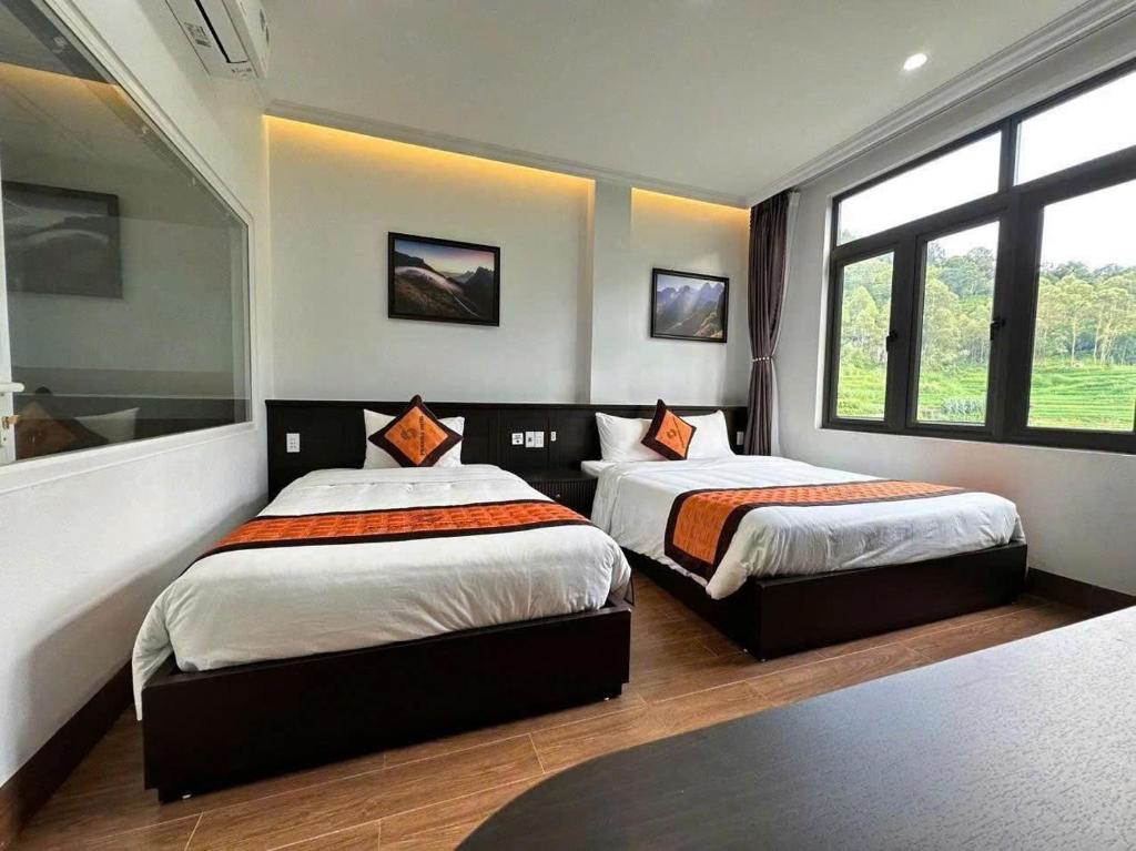 two beds in a room with two windows at Friendly Hotel in Dồng Văn