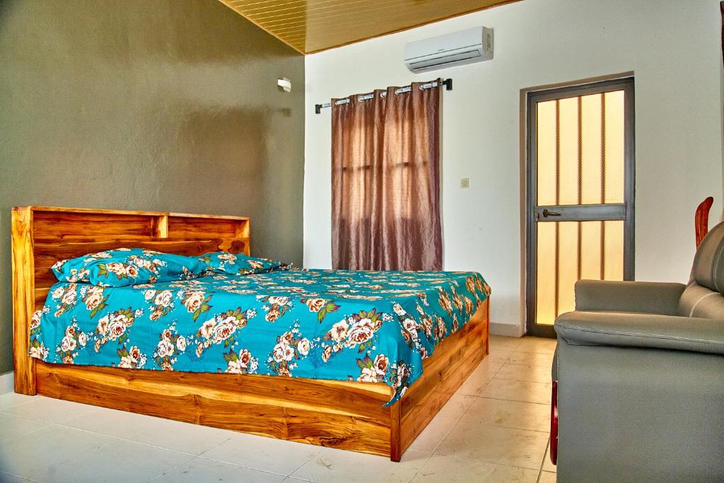 a bedroom with a bed with a blue comforter and a couch at Appartement meublé AKAPEO in Lomé