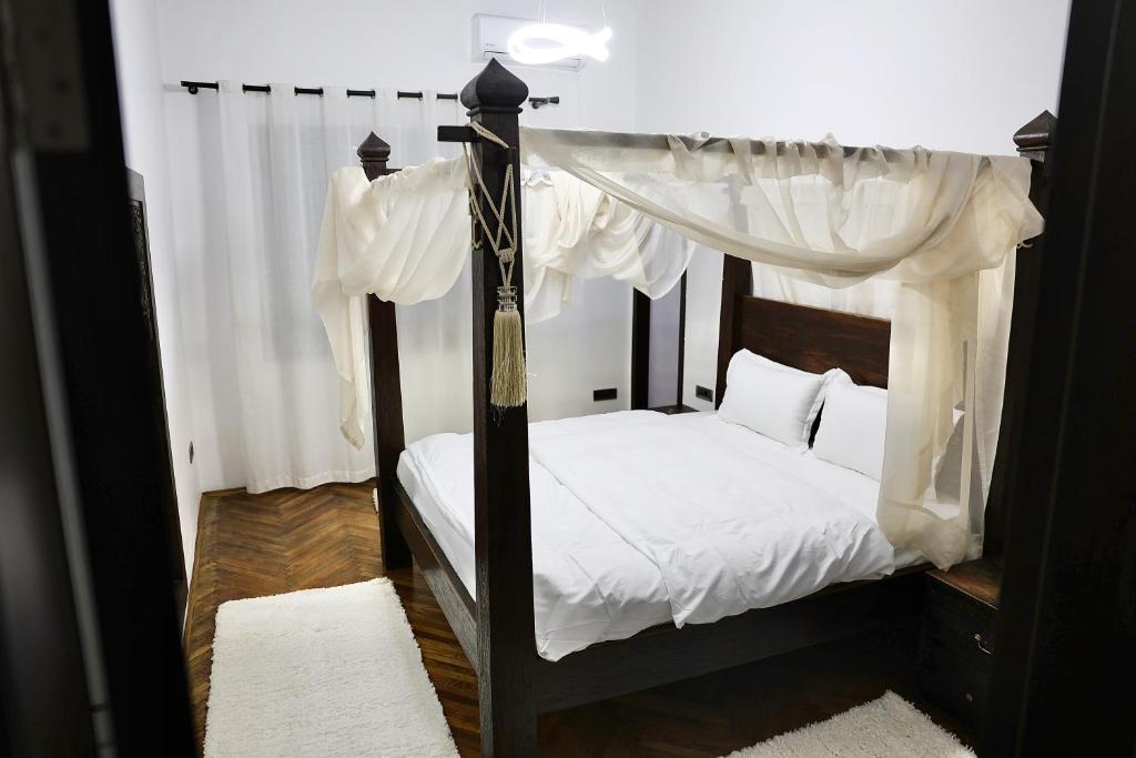 ein Schlafzimmer mit einem schwarzen Himmelbett mit weißer Bettwäsche in der Unterkunft The Central Spot - Grand Suite in Tirana