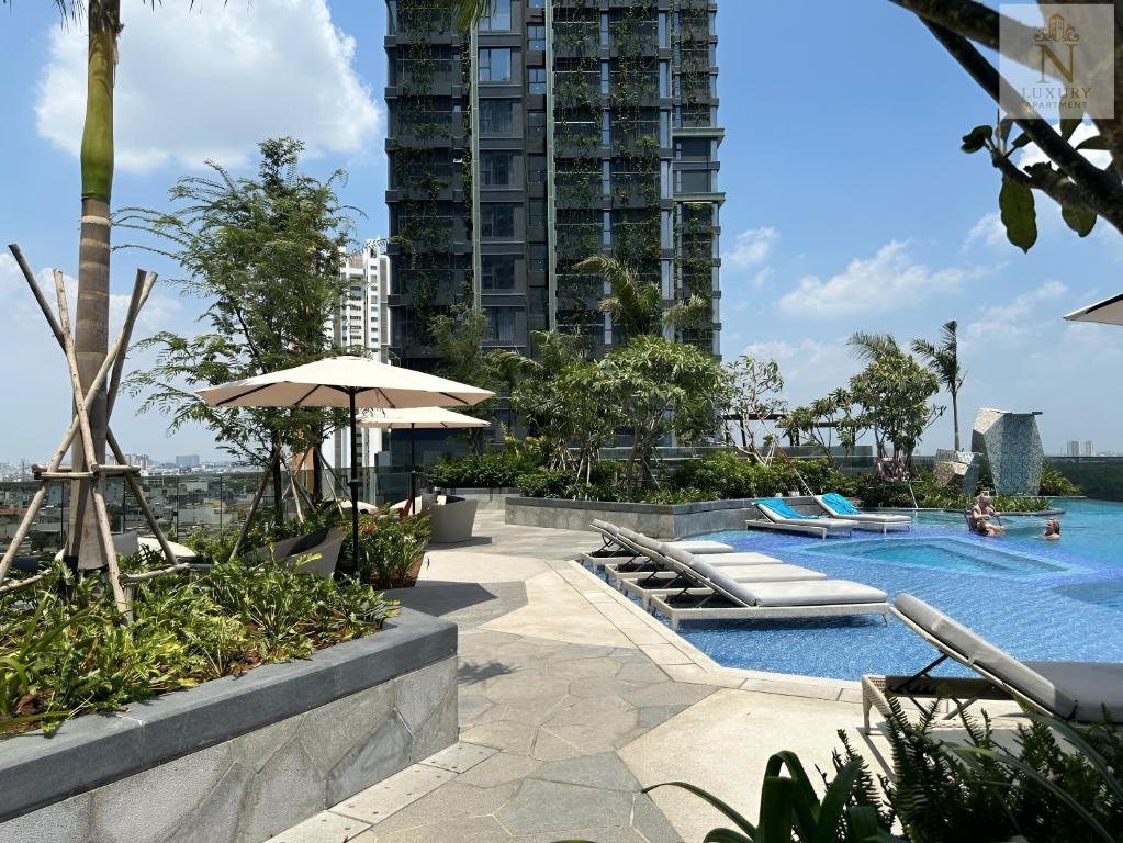 une piscine avec un parasol et un bâtiment dans l'établissement Lumiere Garden Hideaway, à Hô-Chi-Minh-Ville