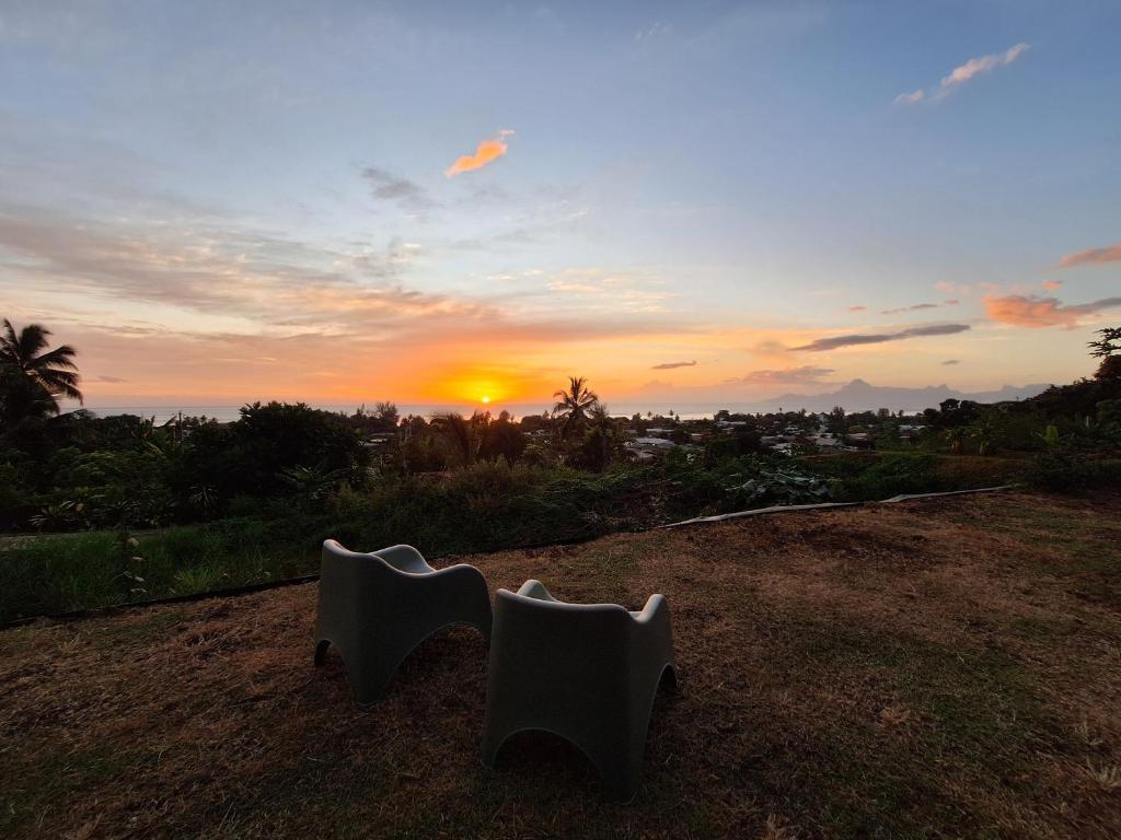 Una vista del atardecer desde una colina con dos sillas blancas en Fare Pūnano, en Punaauia