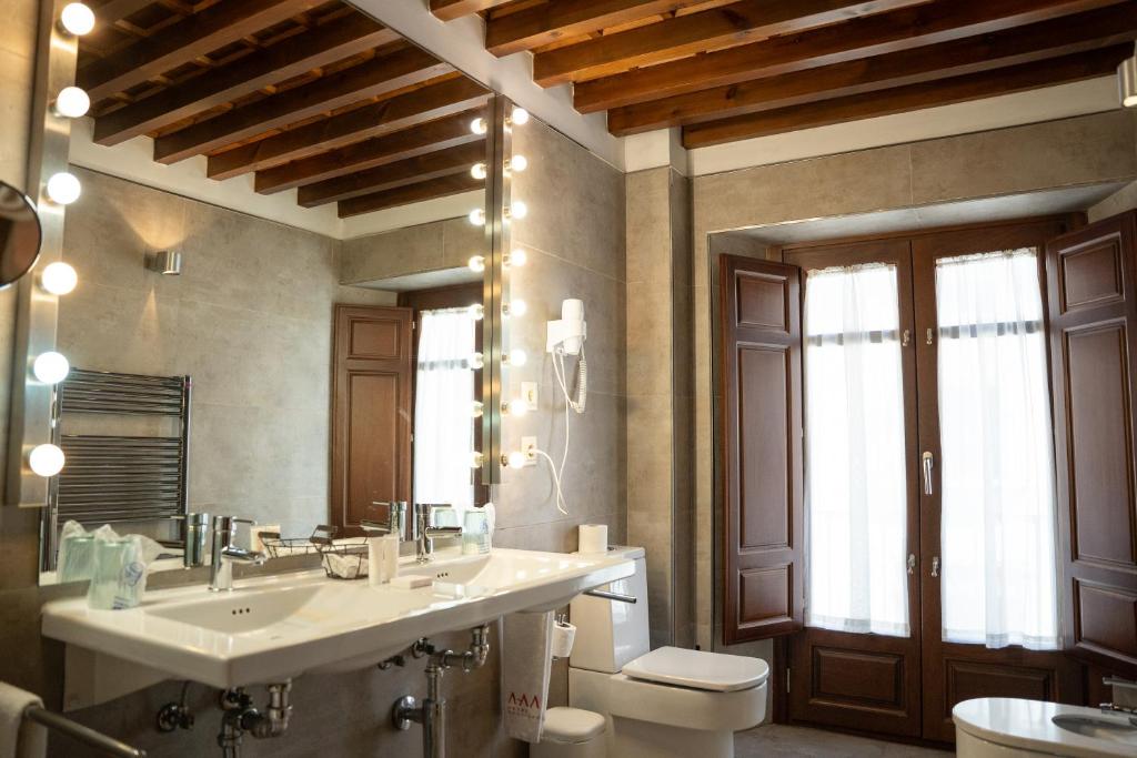 Un baño con lavabo, inodoro y espejo. en Gar Anat Hotel Boutique, en Granada