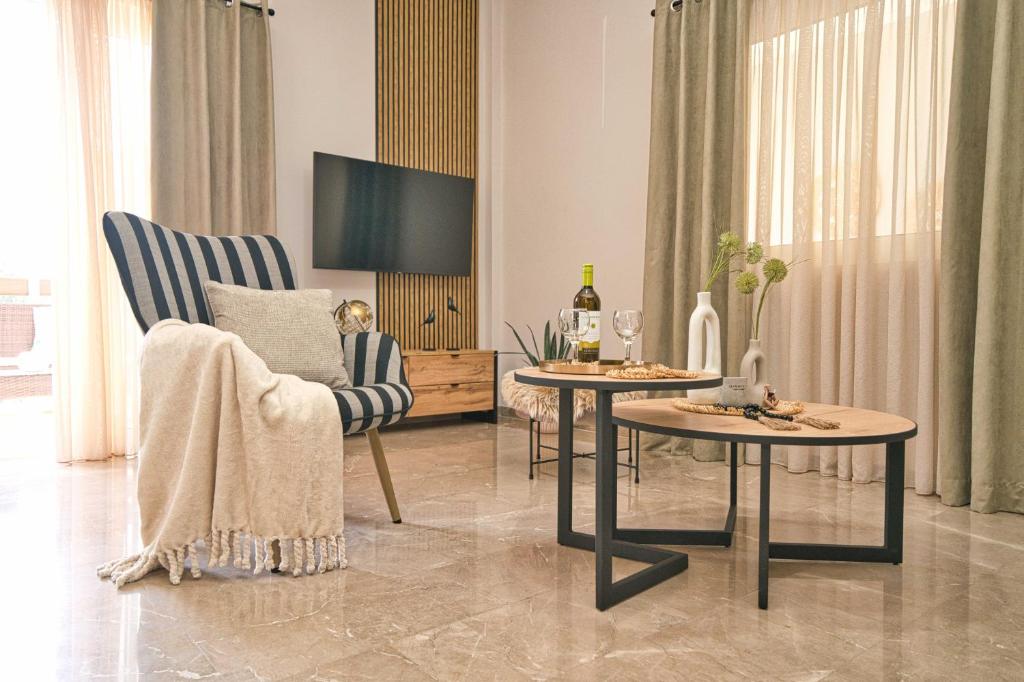 ein Wohnzimmer mit zwei Tischen und einem Fernseher in der Unterkunft Filoxenia MG Amazon Home in Nafplio