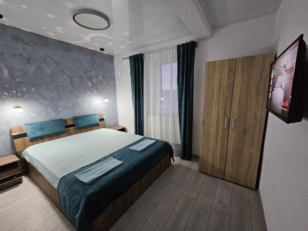 ein Schlafzimmer mit einem Bett und einem Flachbildfernseher in der Unterkunft Vila Kalibu 3 in Iaşi