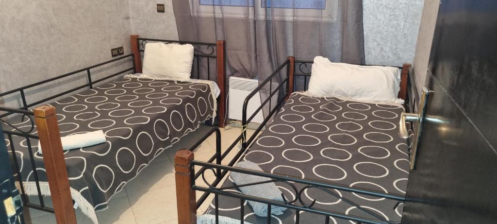 two twin beds in a room with a window at Vip apartment in Fès