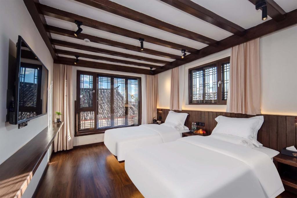 麗江市にあるGolden Dragon's Mountain Glow Innの窓付きの客室で、白いベッド2台が備わります。