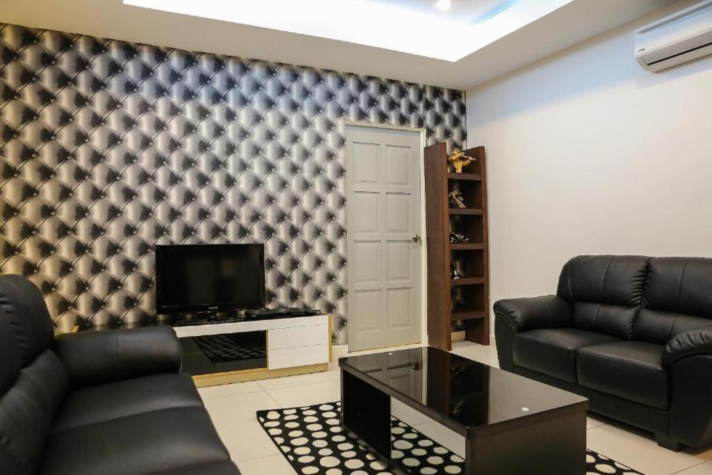a living room with black leather furniture and a tv at Ipoh Apartment Suites in Ipoh