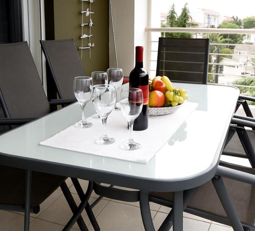 a white table with wine glasses and a bowl of fruit at Epanomi Apartments in Epanomi