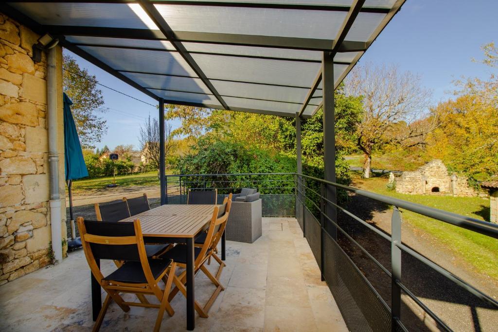 un patio con tavolo e sedie in legno su un balcone di Gite De L'école a La Mouline