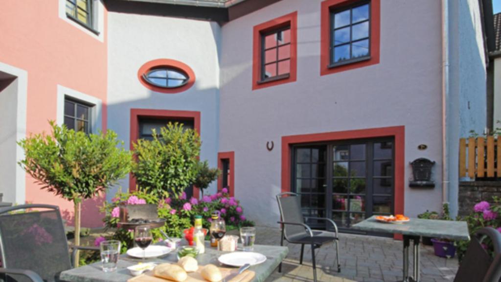 Un patio con una mesa y sillas frente a un edificio. en Im Kylltal, en Malberg