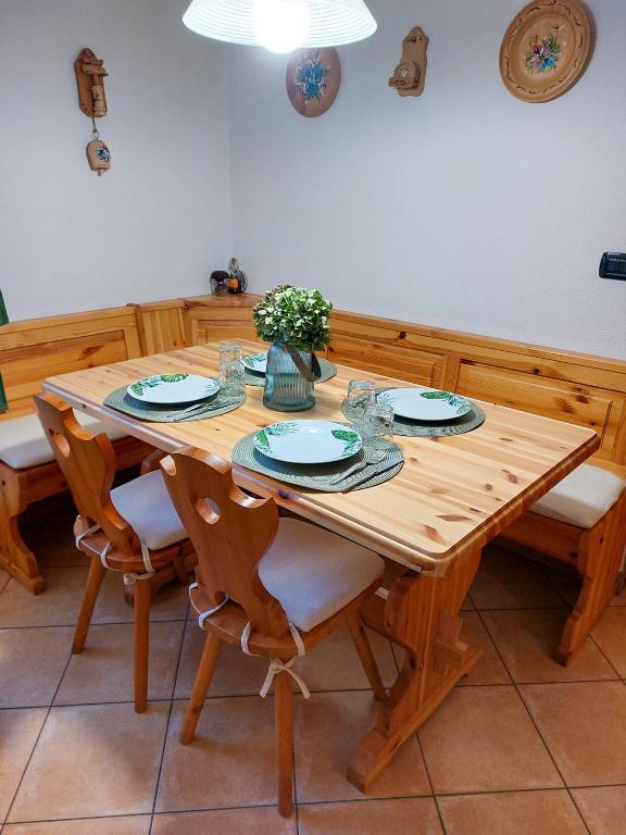 een houten eettafel met stoelen en een vaas met bloemen bij Lo chalet di Lucky in Campodolcino