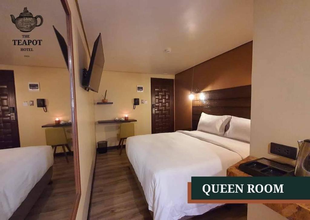 um quarto de hotel com duas camas e um espelho em The Teapot Hotel em Naga