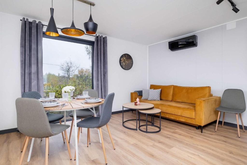 un salon avec une table, des chaises et un canapé dans l'établissement SARNIA HQ Container House in Bielsko-Biała with Garden and Air Conditioning by Noclegi Renters, à Bielsko-Biała