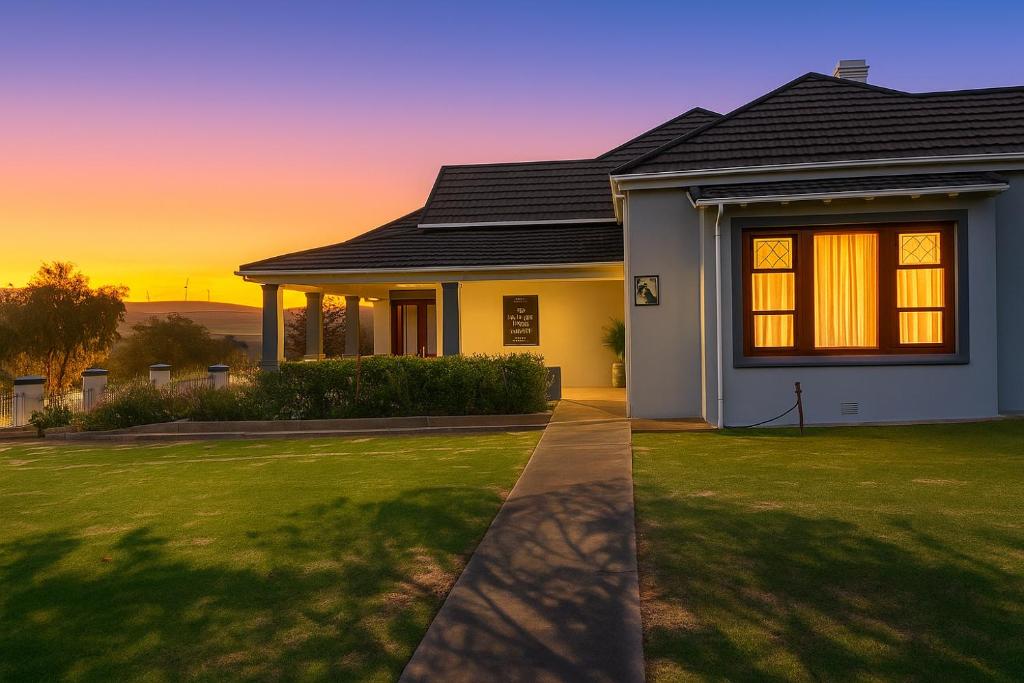 ein Haus mit Rasen vor einem Sonnenuntergang in der Unterkunft The View Guesthouse & Cottage in Caledon