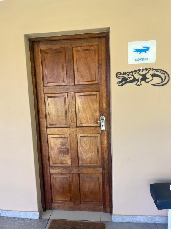 a wooden door in a room with a lizard on the wall at Ingwenya Chalet in Sodwana Bay