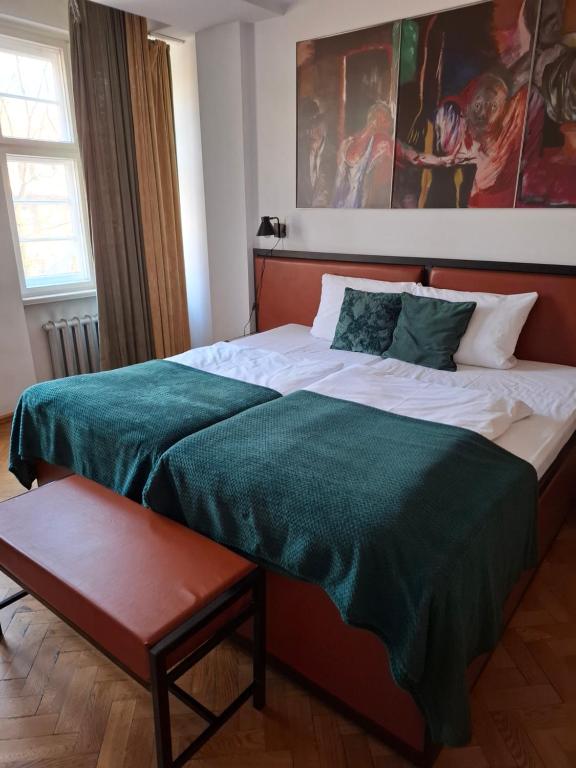 een slaapkamer met een groot bed met groene lakens bij Rooms Bytom in Bytom