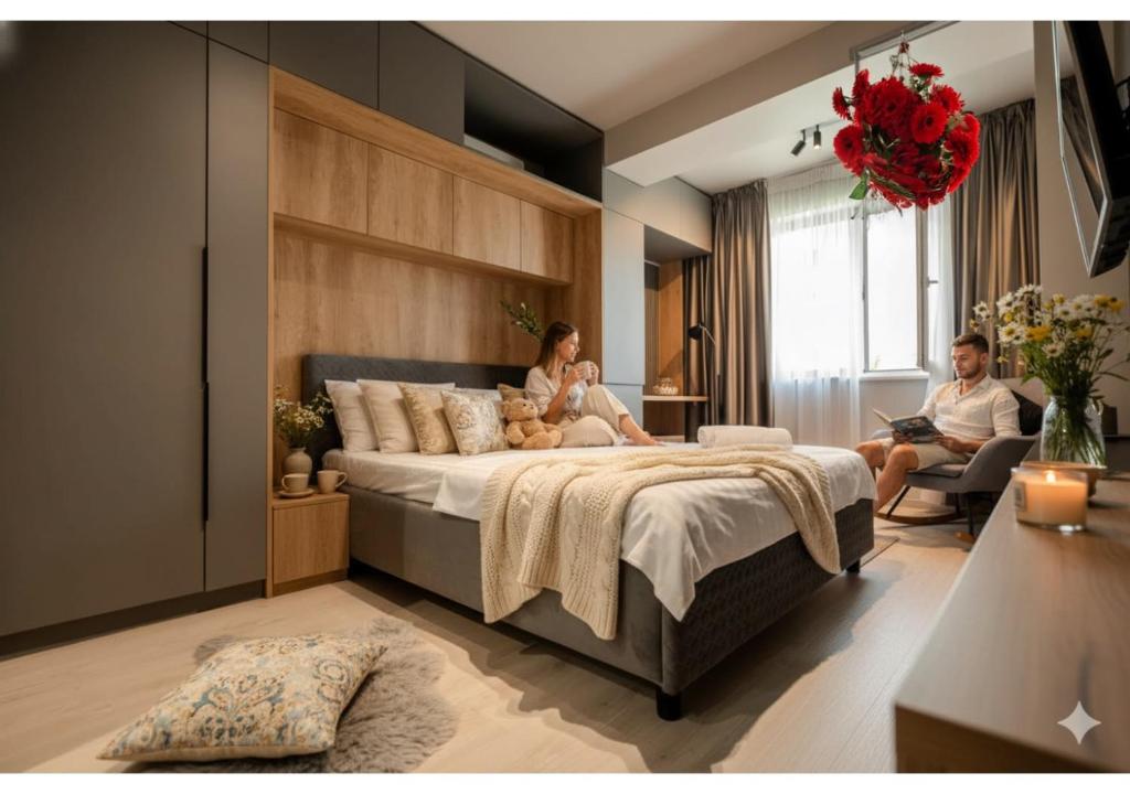 Ein Mann und eine Frau sitzen auf einem Bett in einem Schlafzimmer in der Unterkunft La Gloire by Blvd 8B2 - Premium Studio Retreat in Bukarest