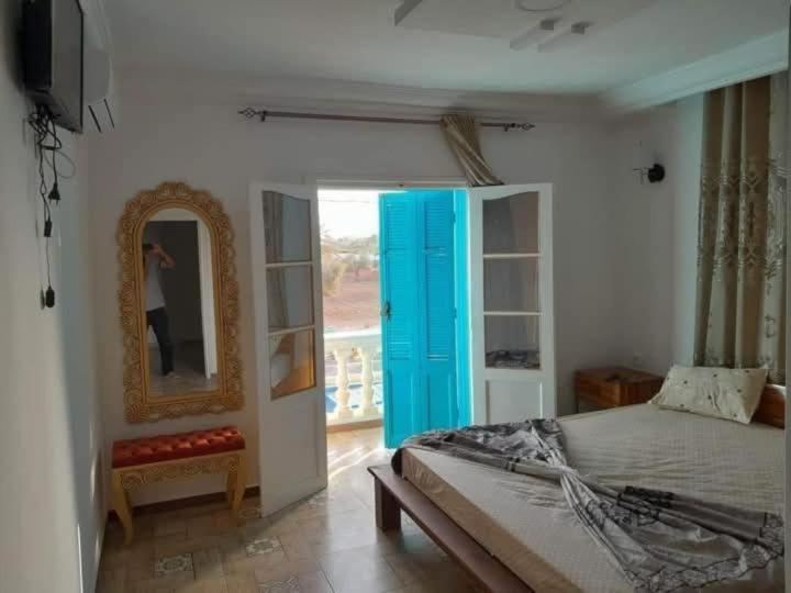 a bedroom with a bed with a blue door and a mirror at Villa des deux frères in Midoun