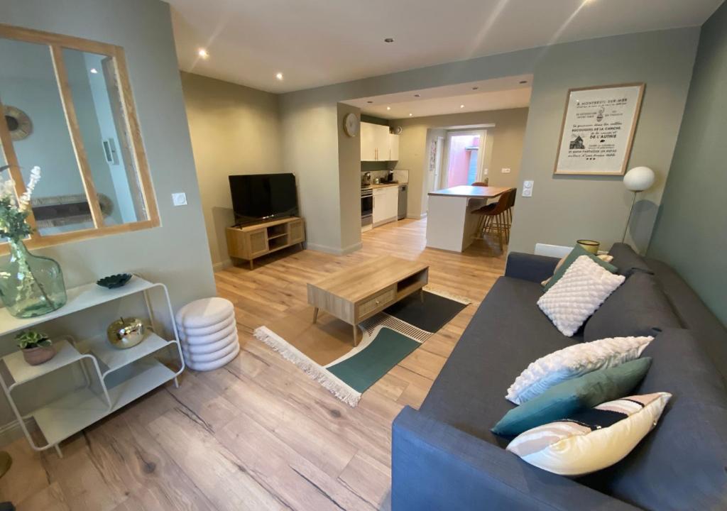 La Lucienne - Cœur de ville avec un extérieur في مونتروي-سور-مير: غرفة معيشة مع أريكة زرقاء ومطبخ