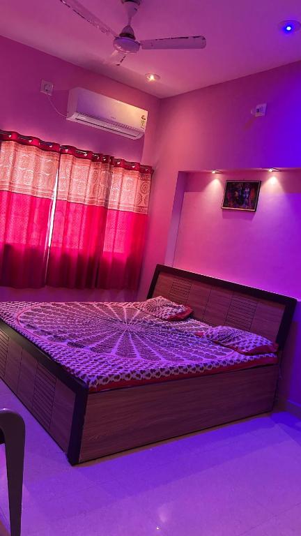 a bedroom with a bed with purple lighting at Dwarka Home Stay in Dwarka