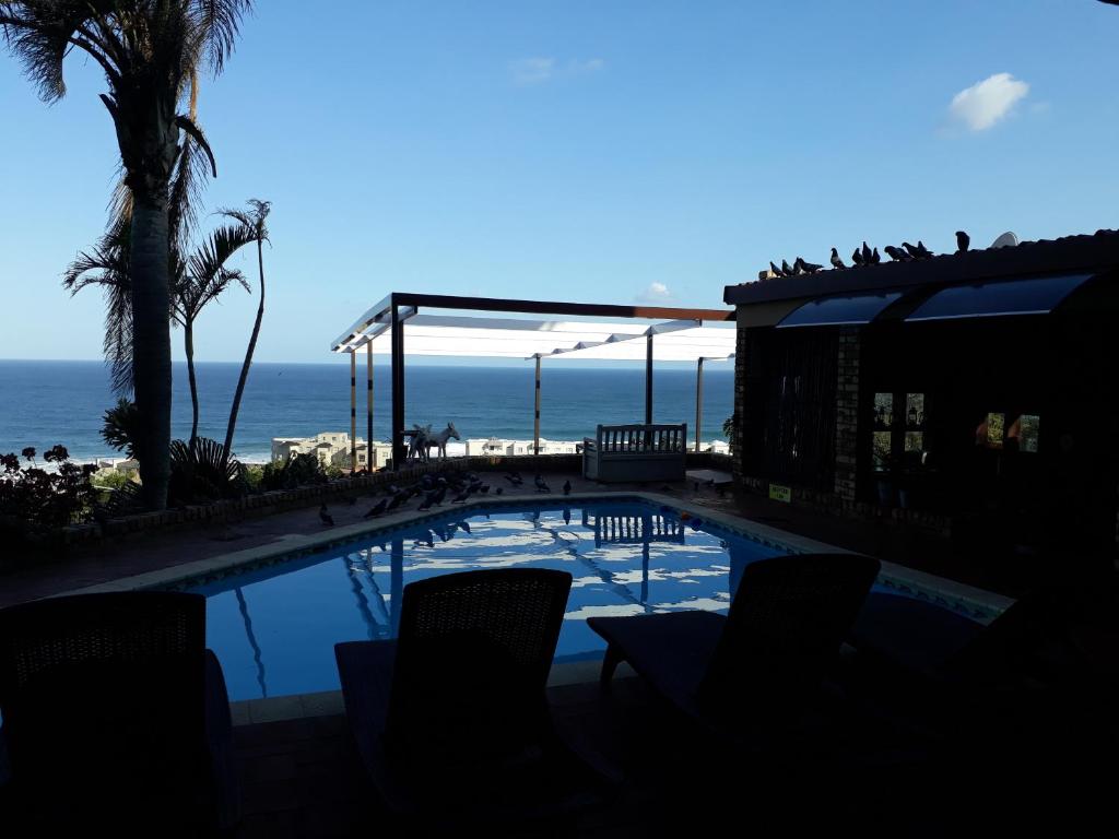 a swimming pool with the ocean in the background at The Albatros Guesthouse in Margate