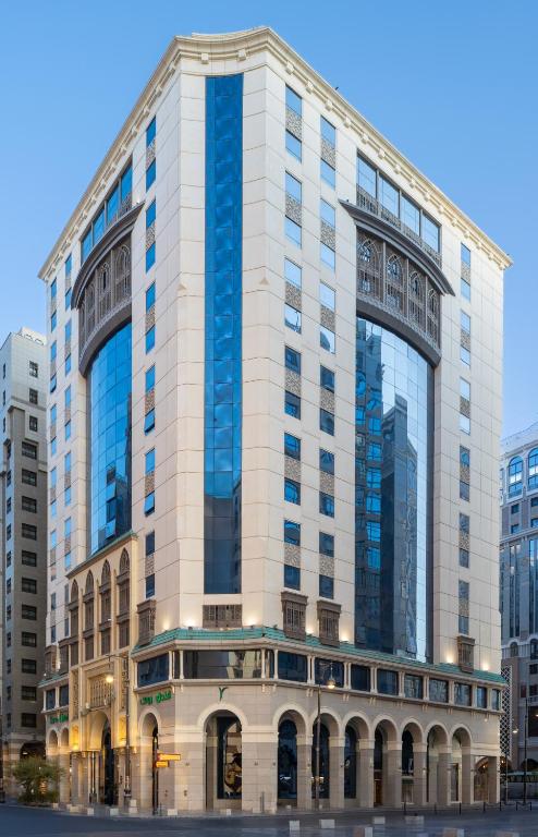 a tall white building with a building at Ruve Al Madinah Hotel in Medina