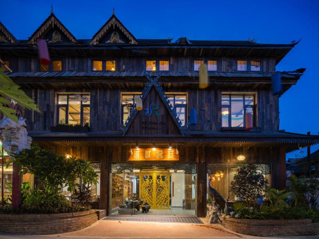 een groot houten gebouw met een voordeur 's nachts bij 22 Garden House in Jinghong