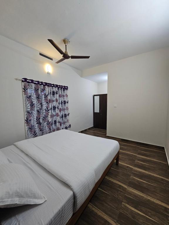 a bedroom with a bed and a ceiling fan at Mount wave Pool villa in Wayanad