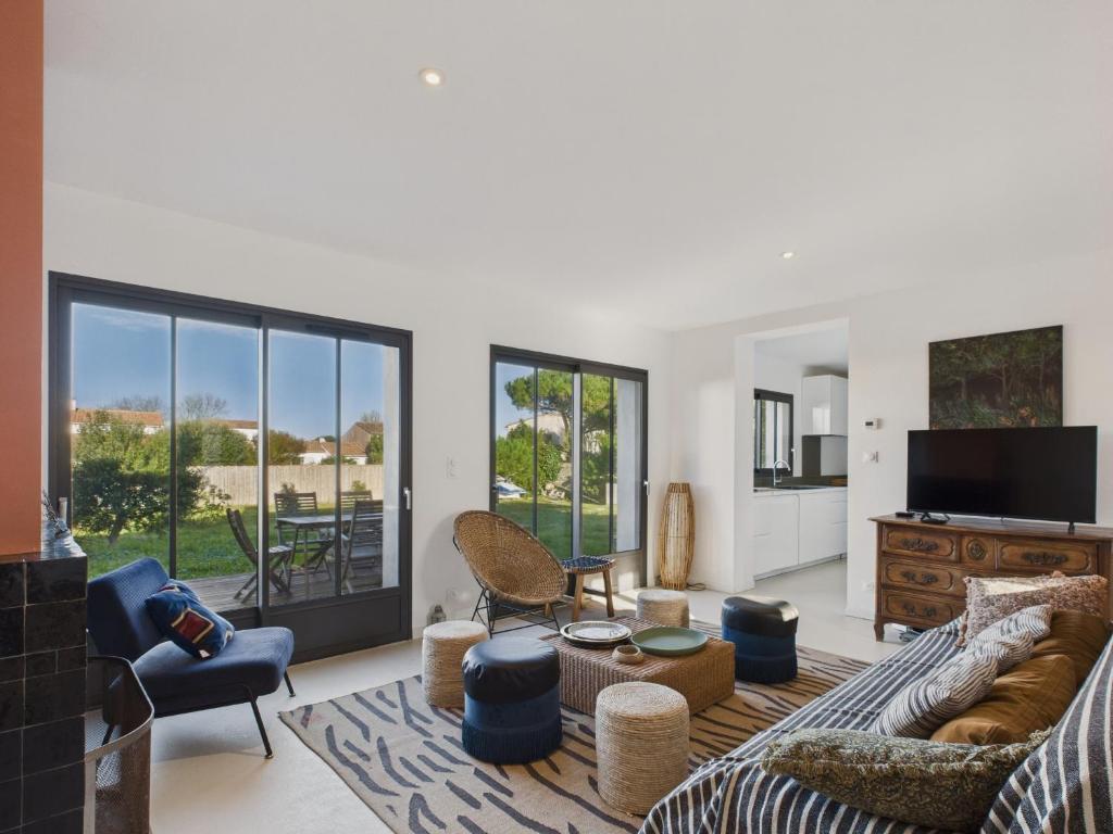 a living room with a couch and chairs and a tv at 400m de la plage, jardin, maison pour 8 in Le Gillieux