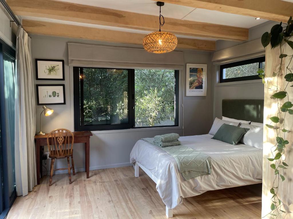 ein Schlafzimmer mit einem Bett, einem Schreibtisch und Fenstern in der Unterkunft Olive Cottage Scarborough Seaside Village in Scarborough