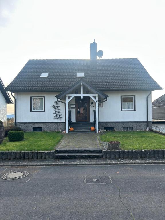 una casa bianca con portico e vialetto di Ferienwohnung Hocheifelblick a Reifferscheid