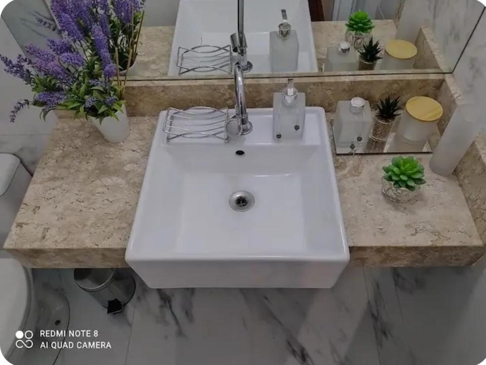 a white sink in a bathroom with flowers at Hospedagem Altas da Quitéria Suíte 01 in Catas Altas