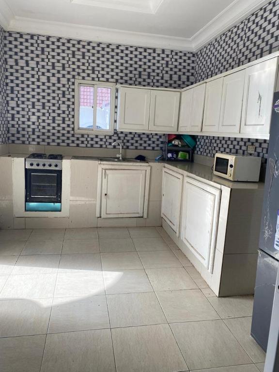 a kitchen with white cabinets and a tile floor at Apartment Brusubi in Mbarra Kunku