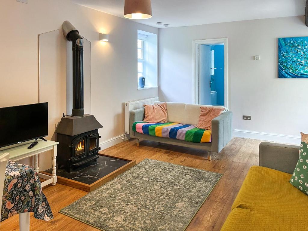 un salon avec une cheminée et un canapé dans l'établissement Bluebell Cottage, à South Brent