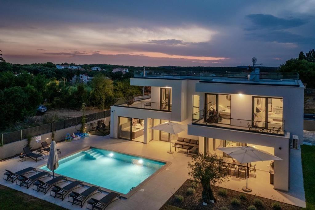 a large house with a swimming pool in front of it at Villa 7Eight Banjole in Banjole