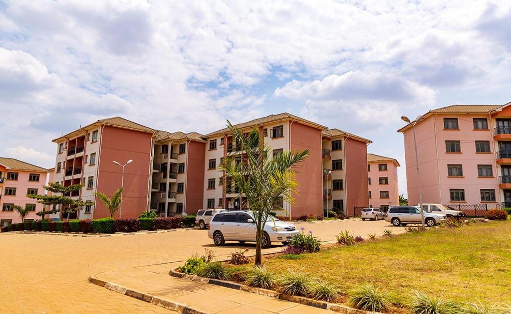 a row of apartment buildings with cars parked in a parking lot at Elegant and Modern Homes, 2BR unit in a secure estate near the golf course in Mbarara