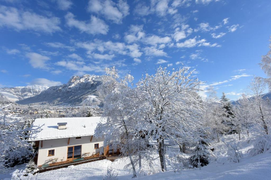 a house covered in snow with mountains in the background at B&B Mas de Lagorae in Tesero