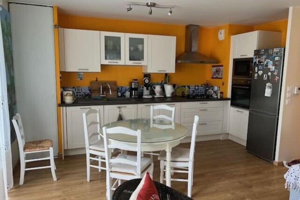 a kitchen with a table and chairs and a refrigerator at Comfort & quiet with garden in Saint-herblain in Saint-Herblain