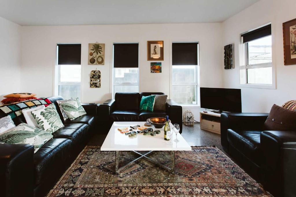 a living room with a couch and a table at Surf's Up - pet-friendly Fitzroy lifestyle home in New Plymouth